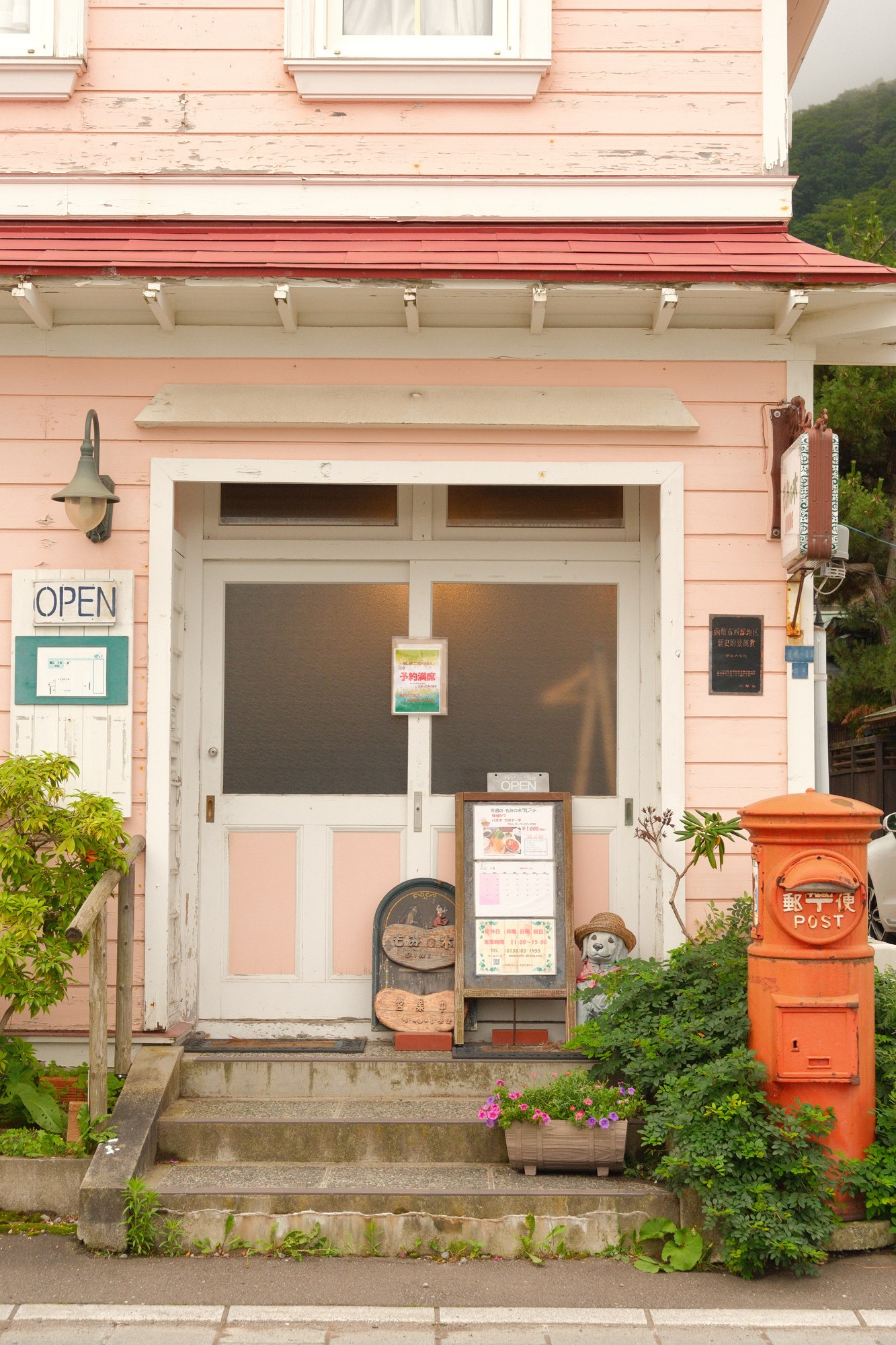 A pastel pink house with green shutters